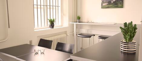 Una sala de conferencias moderna con una mesa grande, sillas negras y plantas en macetas.