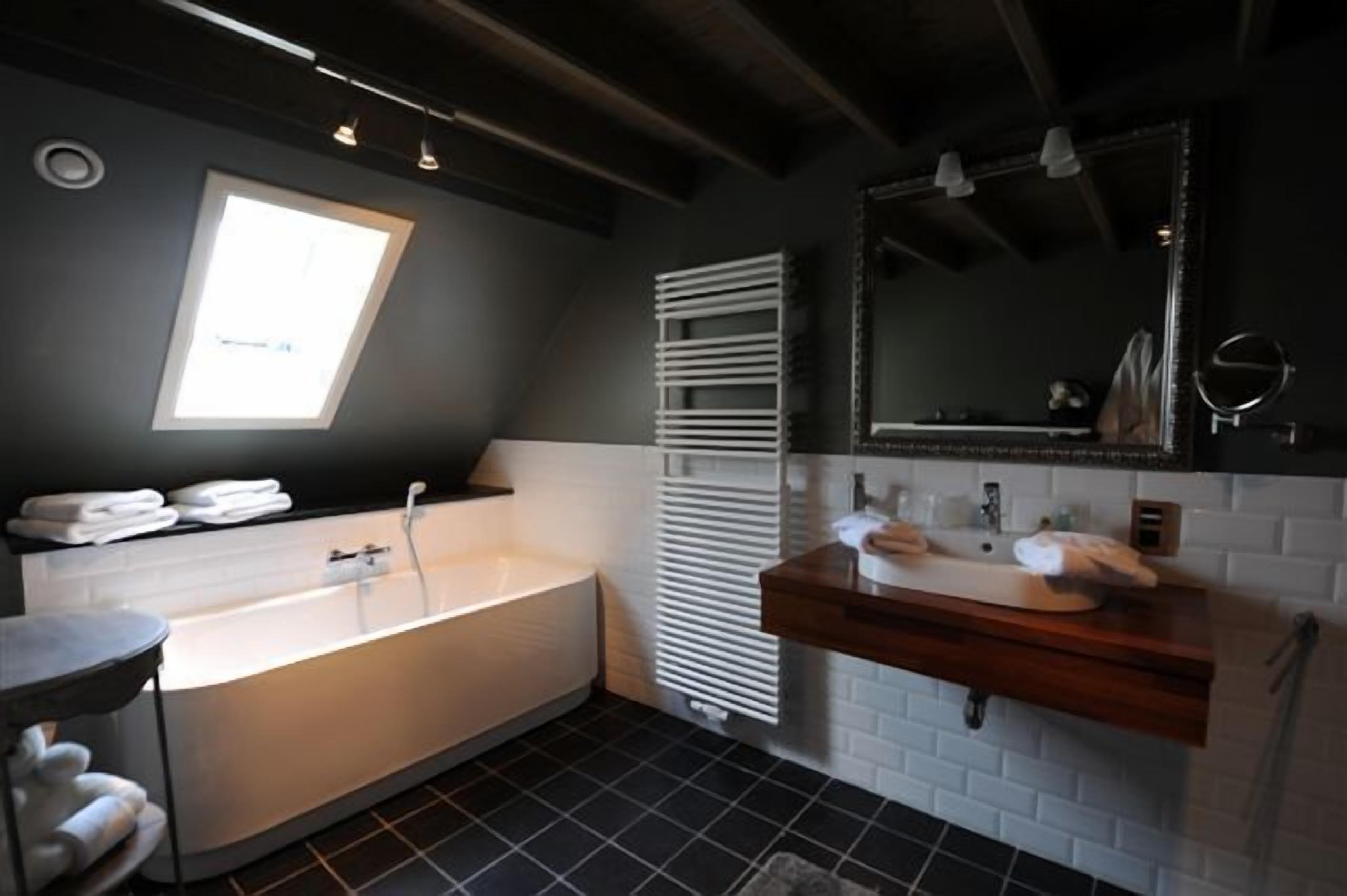 Een moderne badkamer met een vrijstaand bad, een wastafel met spiegel en een handdoekrek.