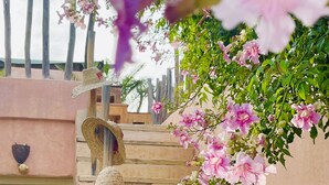 A staircase with a wooden railing, surrounded by pink flowers and a wooden fence. - Riad 144 (Marrakech)