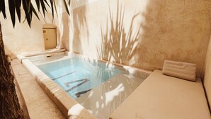 A spa pool with a hot tub, a towel, and a stone wall. - Riad 144 (Marrakech)