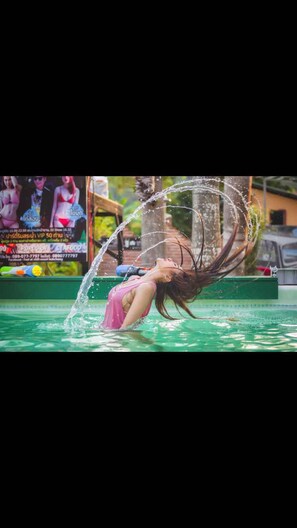 Une personne portant un maillot de bain rose effectue une figure acrobatique dans une piscine.