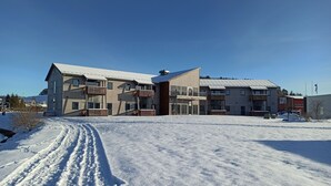 A multi-story building with a snow-covered ground, a clear sky, and a visible path leading to the entrance. - Bjugn Hotell (Orland)