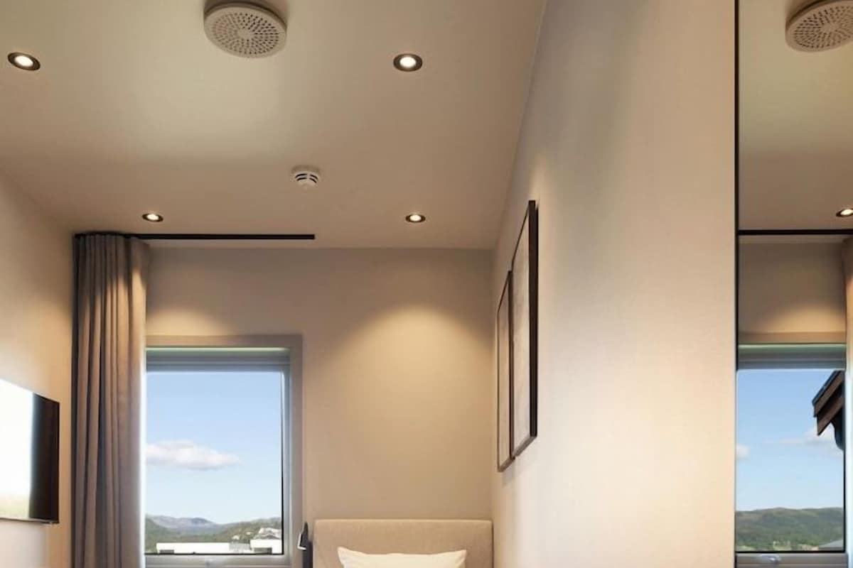 A modern bedroom with a bed, a window, and a mirror.