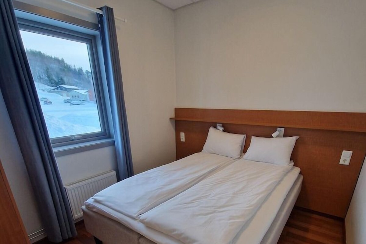 A single bed with a wooden headboard in a room with a window and a radiator.
