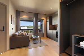 A modern living room with a sofa, a coffee table, and a view of the outdoors through large windows. - Bjugn Hotell (Orland)