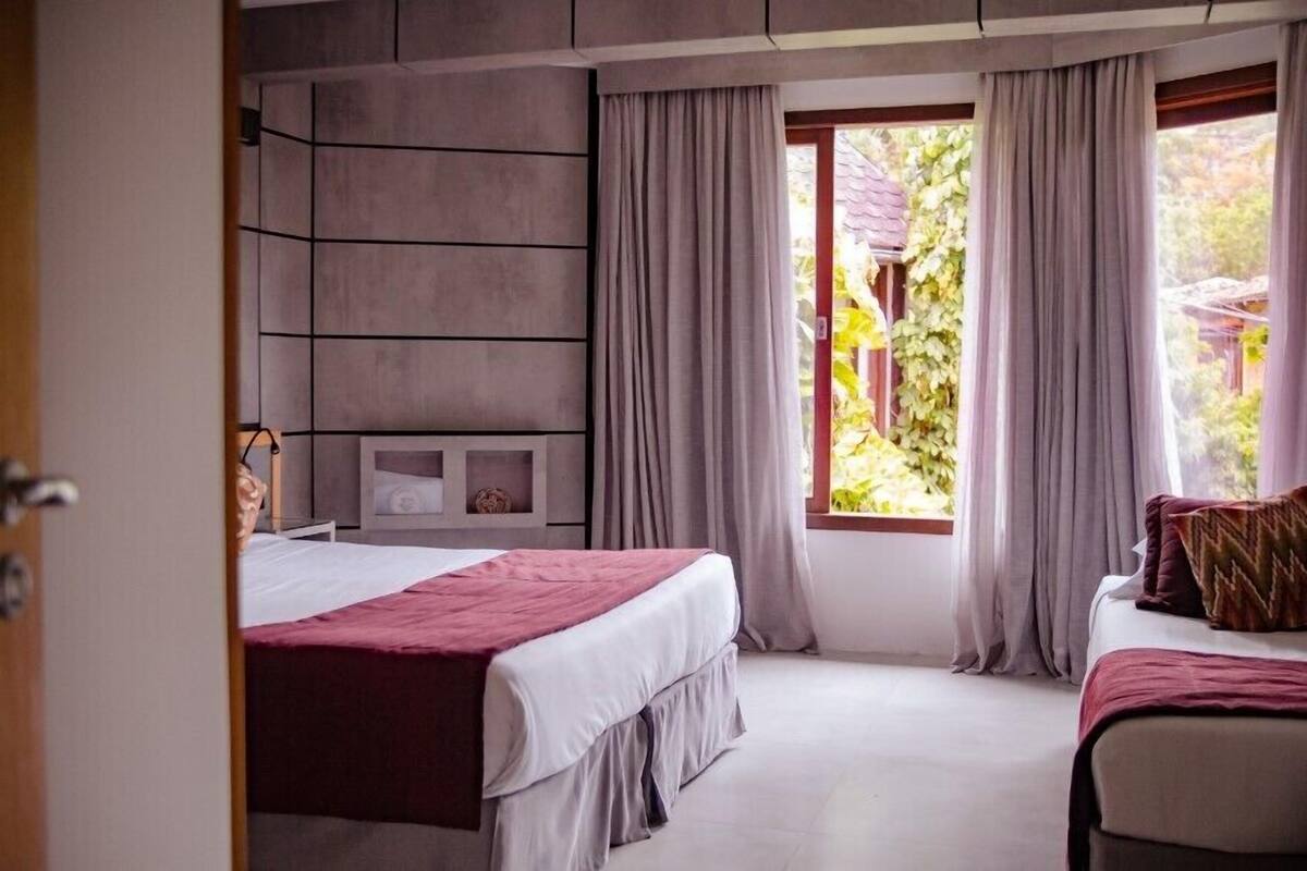 A bedroom with a bed, a bedside table, a wardrobe, and a window with curtains.