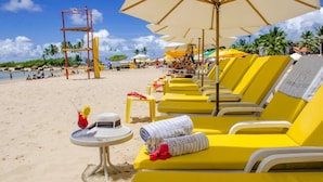 A beachside hotel with yellow lounge chairs, umbrellas, and a lifeguard tower. - Pousada da Torre (Cairu)