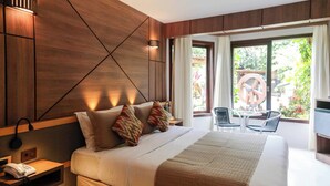 A modern hotel room with a large bed, a bedside table with a phone, and a view of the outdoors through a window. - Pousada da Torre (Cairu)