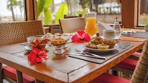 A breakfast table with a glass of orange juice, a plate of muffins, and a bowl of cereal. - Pousada da Torre (Cairu)