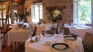 Ein Restaurant mit mehreren Tischen, Steinwänden und einem Kamin.