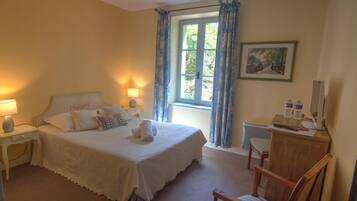 A bedroom with a bed, bedside lamps, a chair, a desk, a window with curtains, and a painting on the wall.