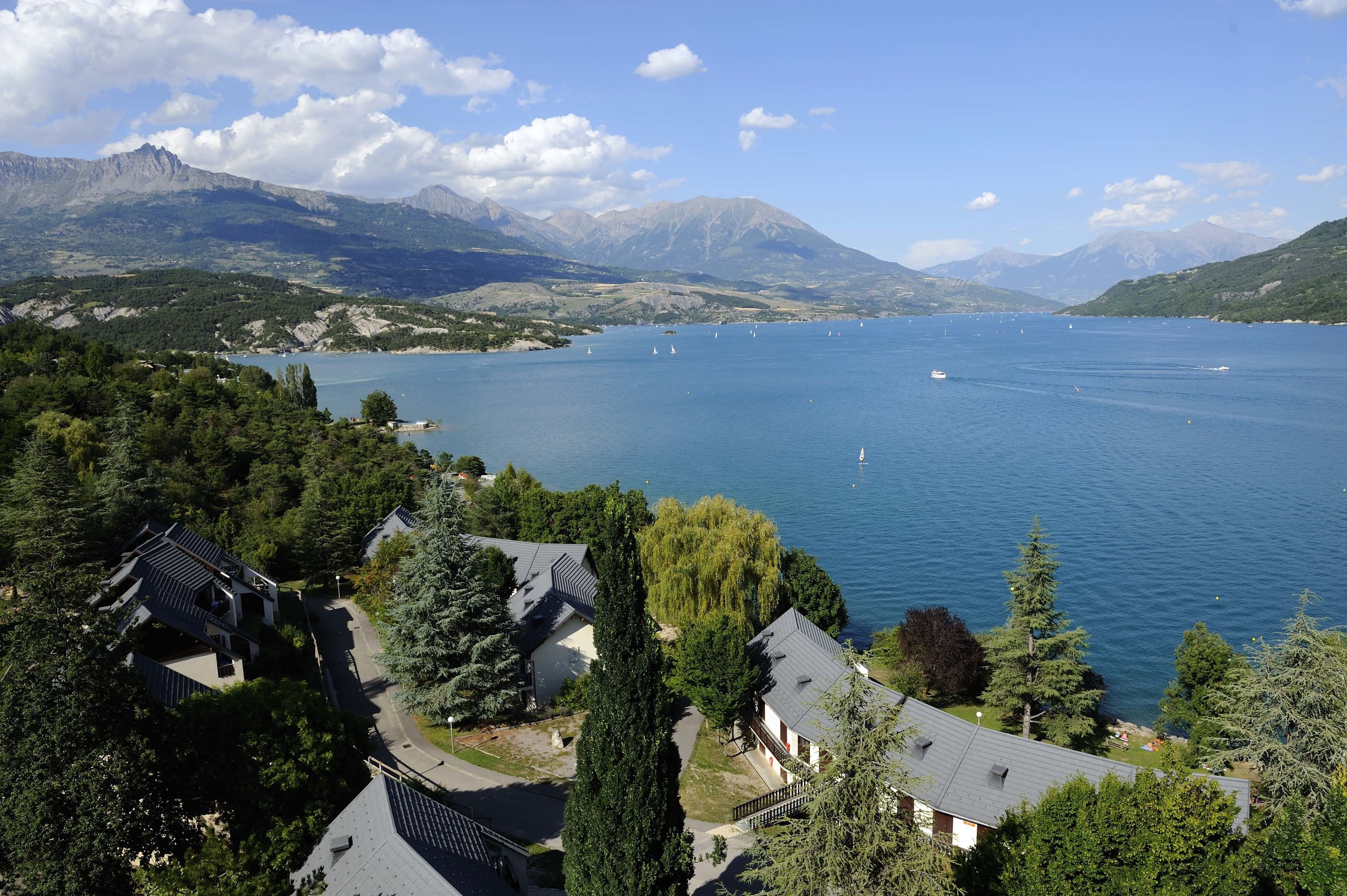 Un lac où l’on peut faire du bateau, entouré de montagnes et de bâtiments résidentiels.