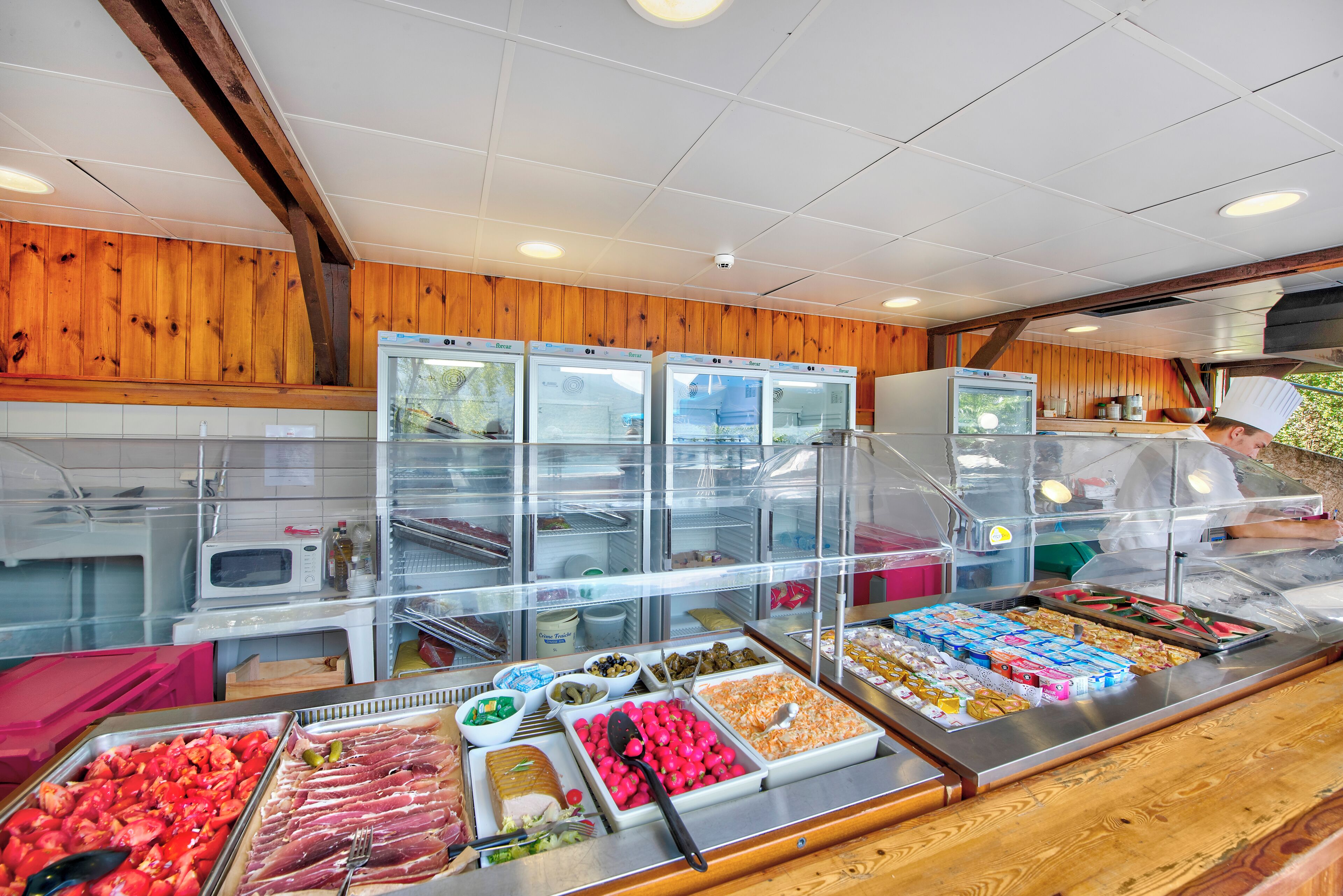 Een buffet met diverse gerechten en een kok die aan het koken is.