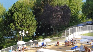A swimming pool with people, surrounded by trees and a view of mountains. - Village Club les Hyvans (Chorges)