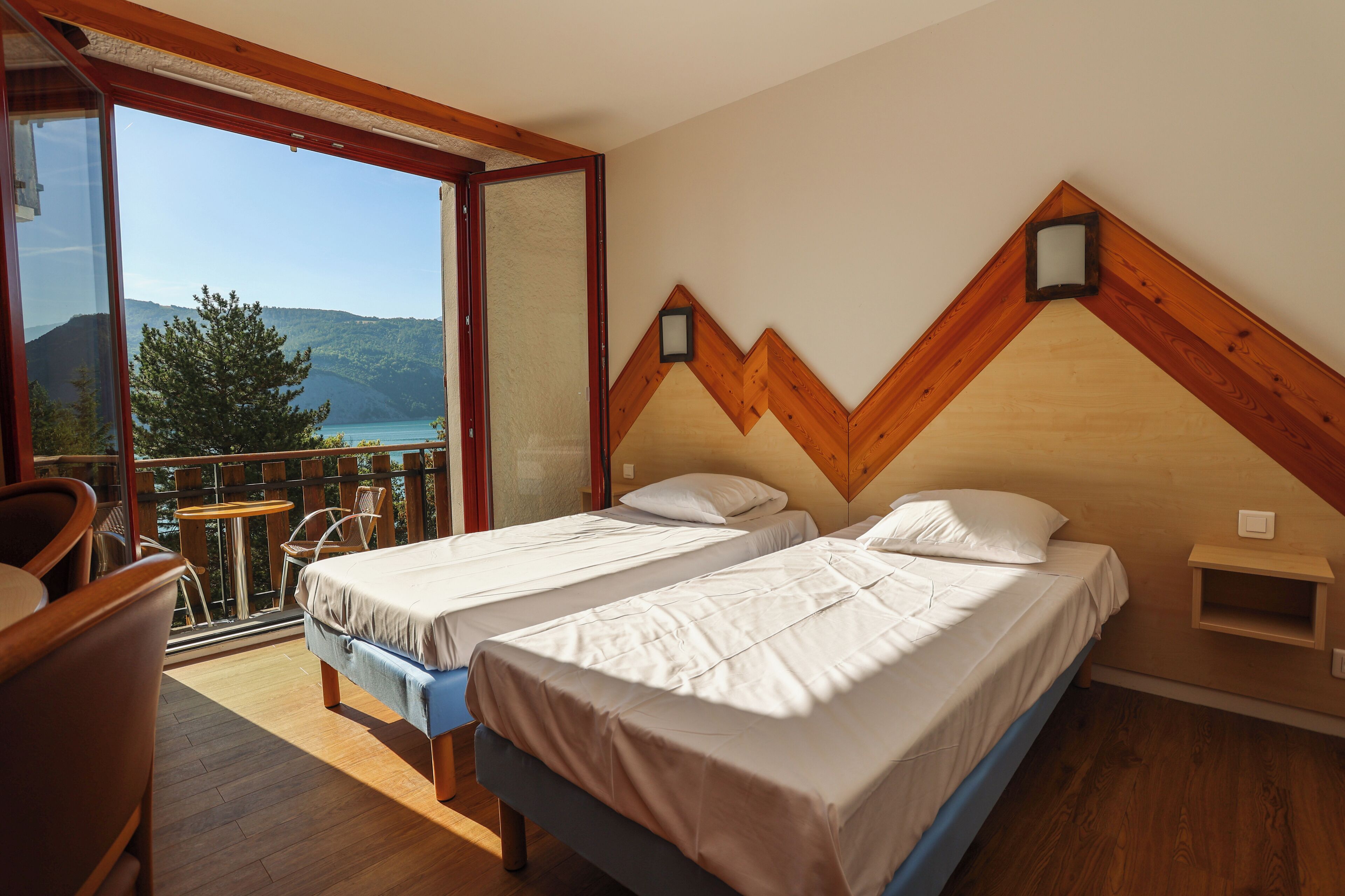 Una camera da letto con due letti, un balcone vista mare e dettagli in legno.