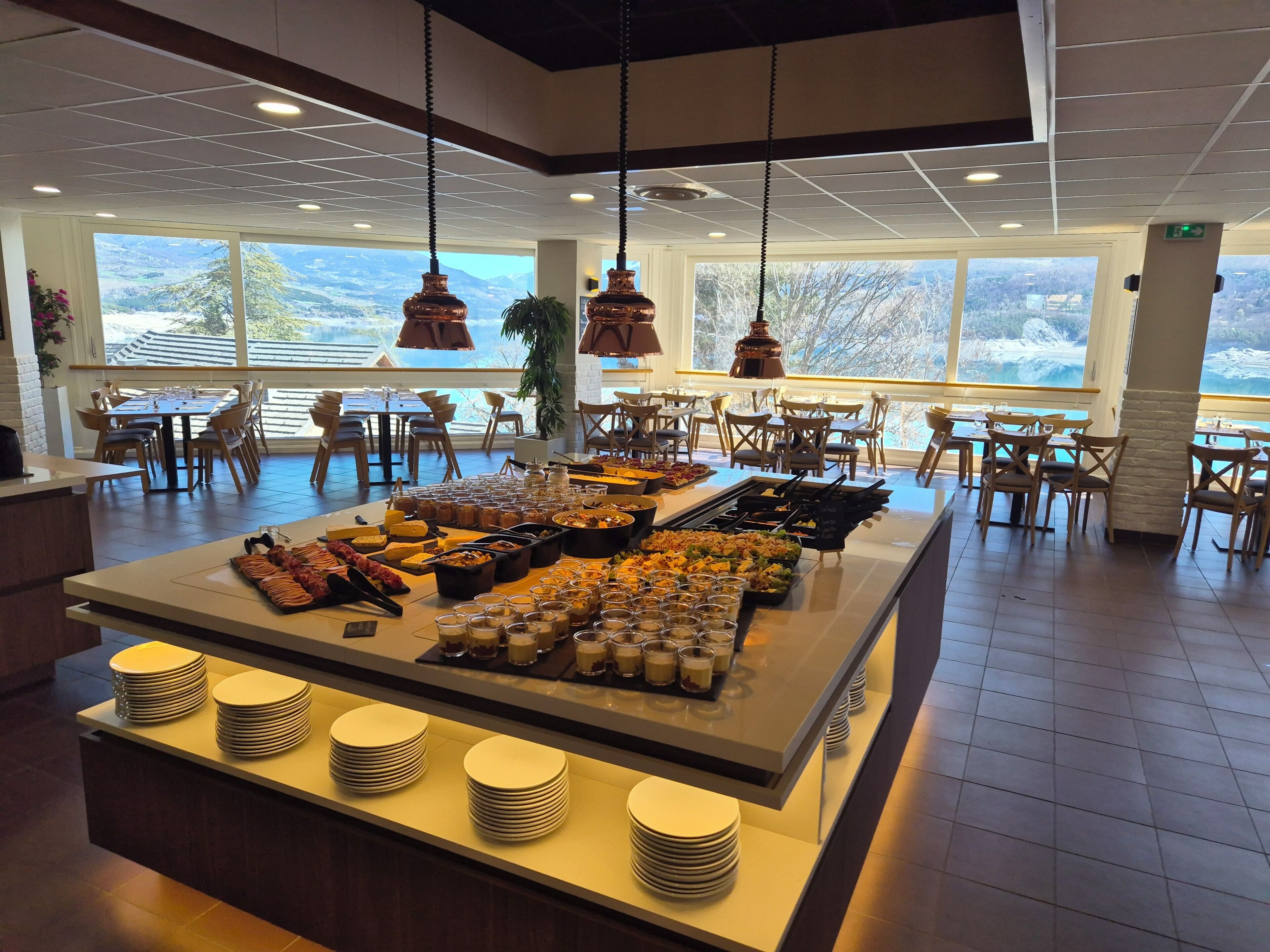 A buffet area with a variety of food items and drinks, surrounded by tables and chairs.
