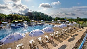A pool area with sun umbrellas, lounge chairs, and a clear view of the sky. - Village Club Kerlannic (Arzon)