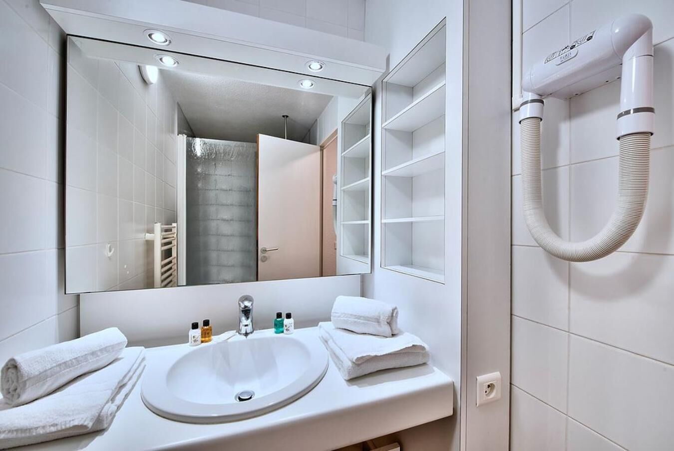 A modern bathroom with a large mirror, a sink, and a hairdryer.
