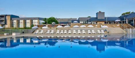 Una piscina al aire libre, sillones reclinables de piscina