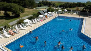 Relax by the pool surrounded by lush greenery and a scenic sea view.