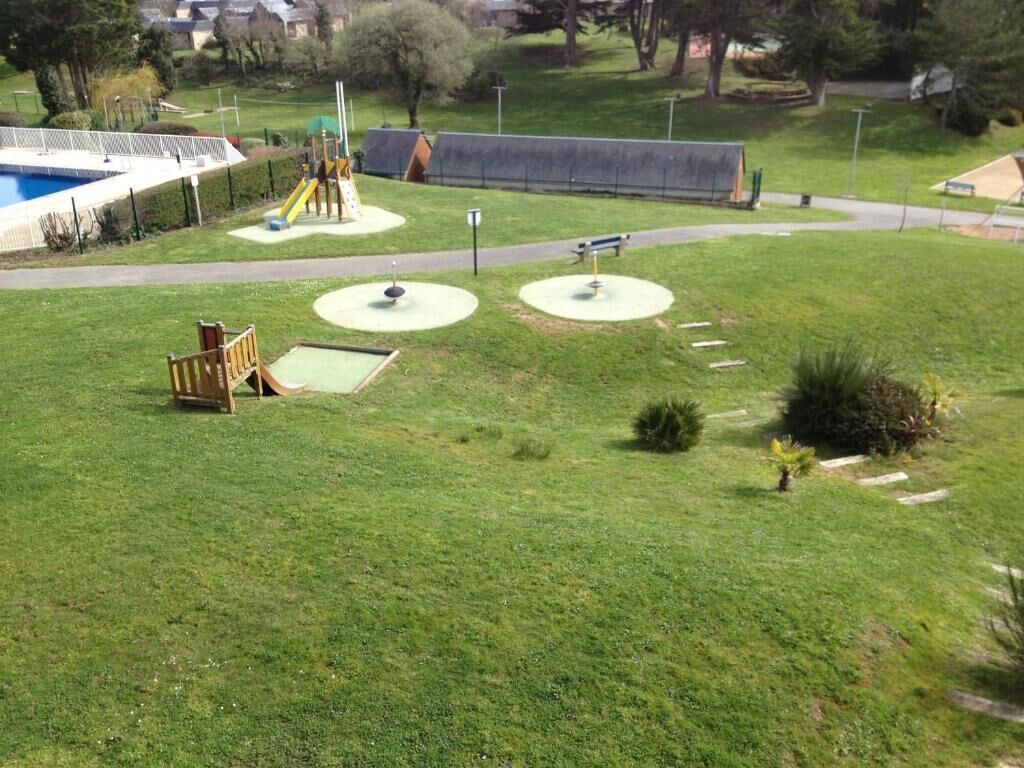 A grassy area with a playground, a small pool, and a walking path.
