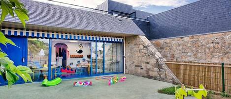 Ein Spielbereich für Kinder mit Rutsche, Schaukeln und einer Kletterkonstruktion.