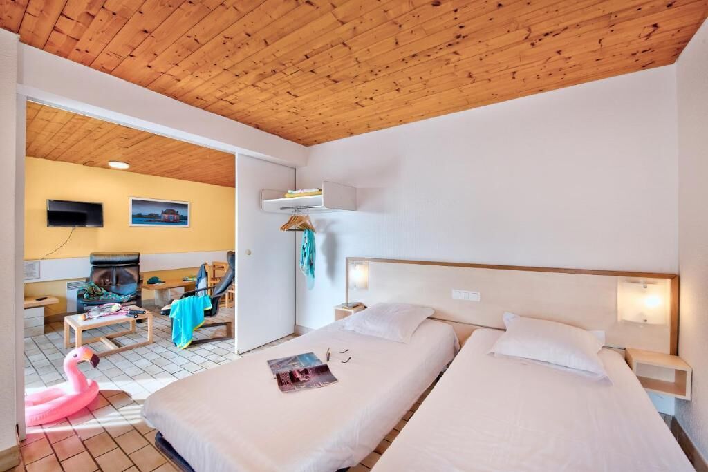 Habitación de hotel con dos camas, techo de madera, televisión y una mesita.