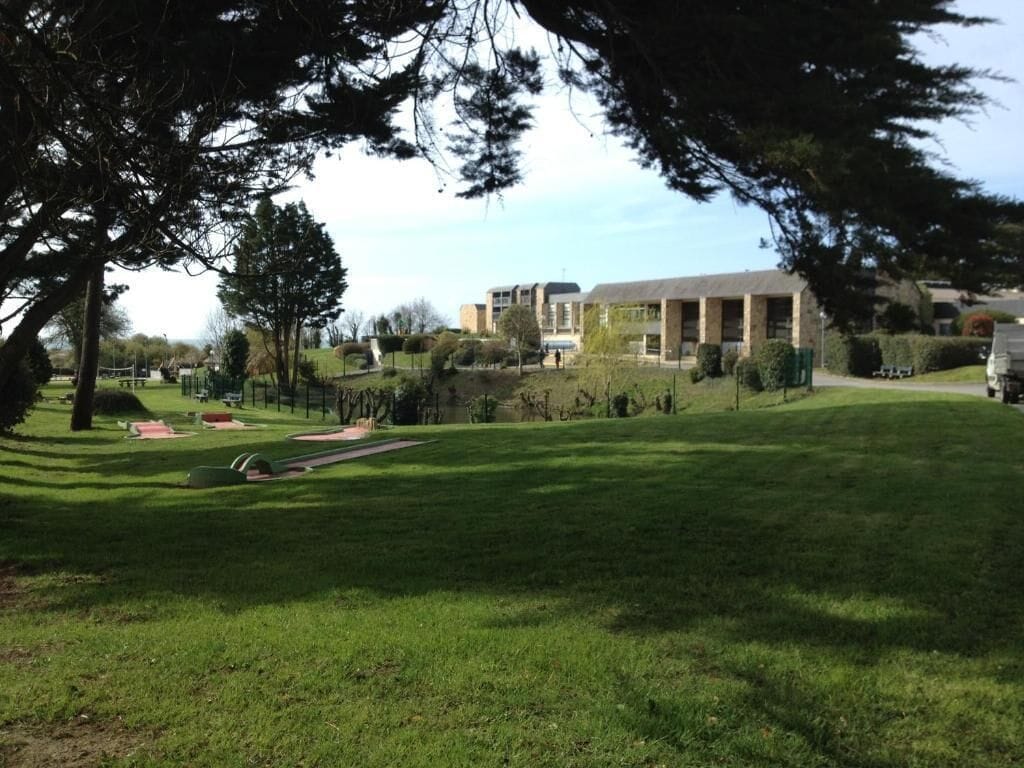 A grassy area with a playground, a building with multiple windows, and a clear sky.