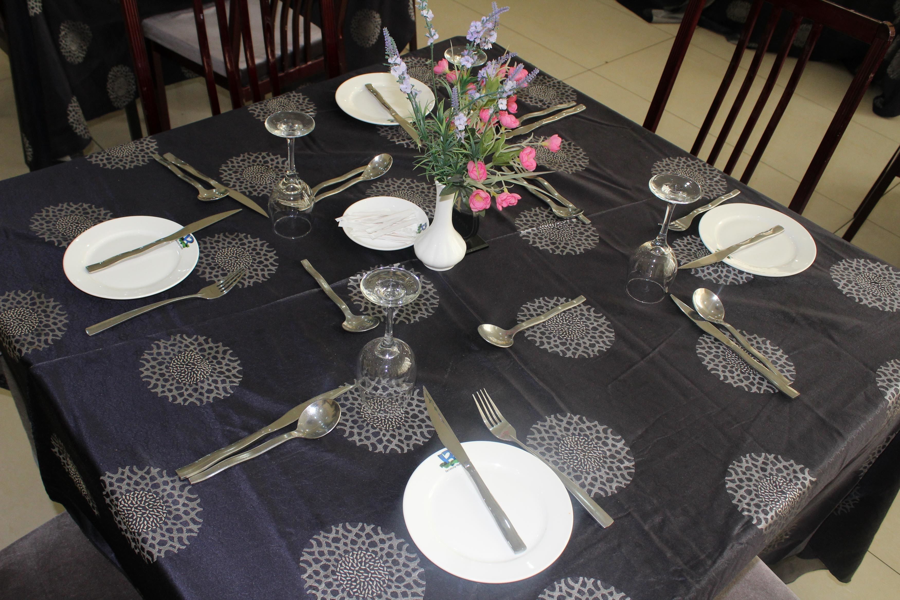 A dining table set for eight with a vase of flowers, silverware, and plates.