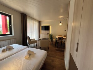 A hotel room with two beds, a dining area, and a TV mounted on the wall.