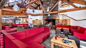 Amplio espacio interior con sofás rojos, mesas de madera y una chimenea de piedra.