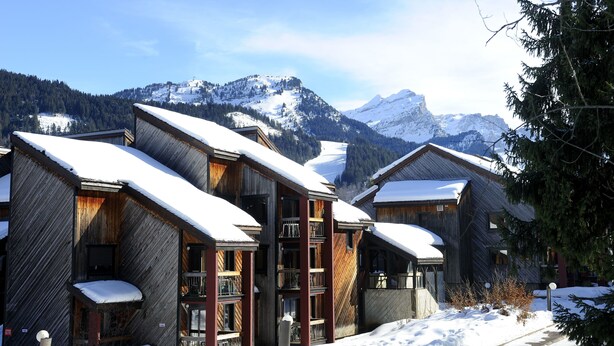 Una cabaña de madera con varios balcones y un paisaje montañoso nevado.