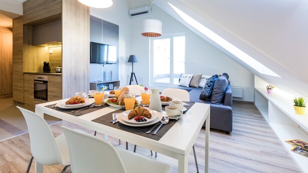 A modern kitchen with a dining area, breakfast setup, and a loft bedroom with a view. - Vagabond Corvin (Budapest)