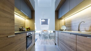A modern kitchen with wooden cabinets, a central island, and a built-in oven. - Vagabond Corvin (Budapest)