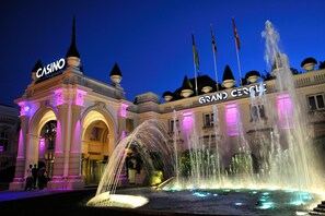 Un imposant bâtiment surmonté d’une grande enseigne indiquant « CASINO » et d’une inscription « GRAND CIRCLE », avec une grande fontaine et une entrée en arc de cercle.