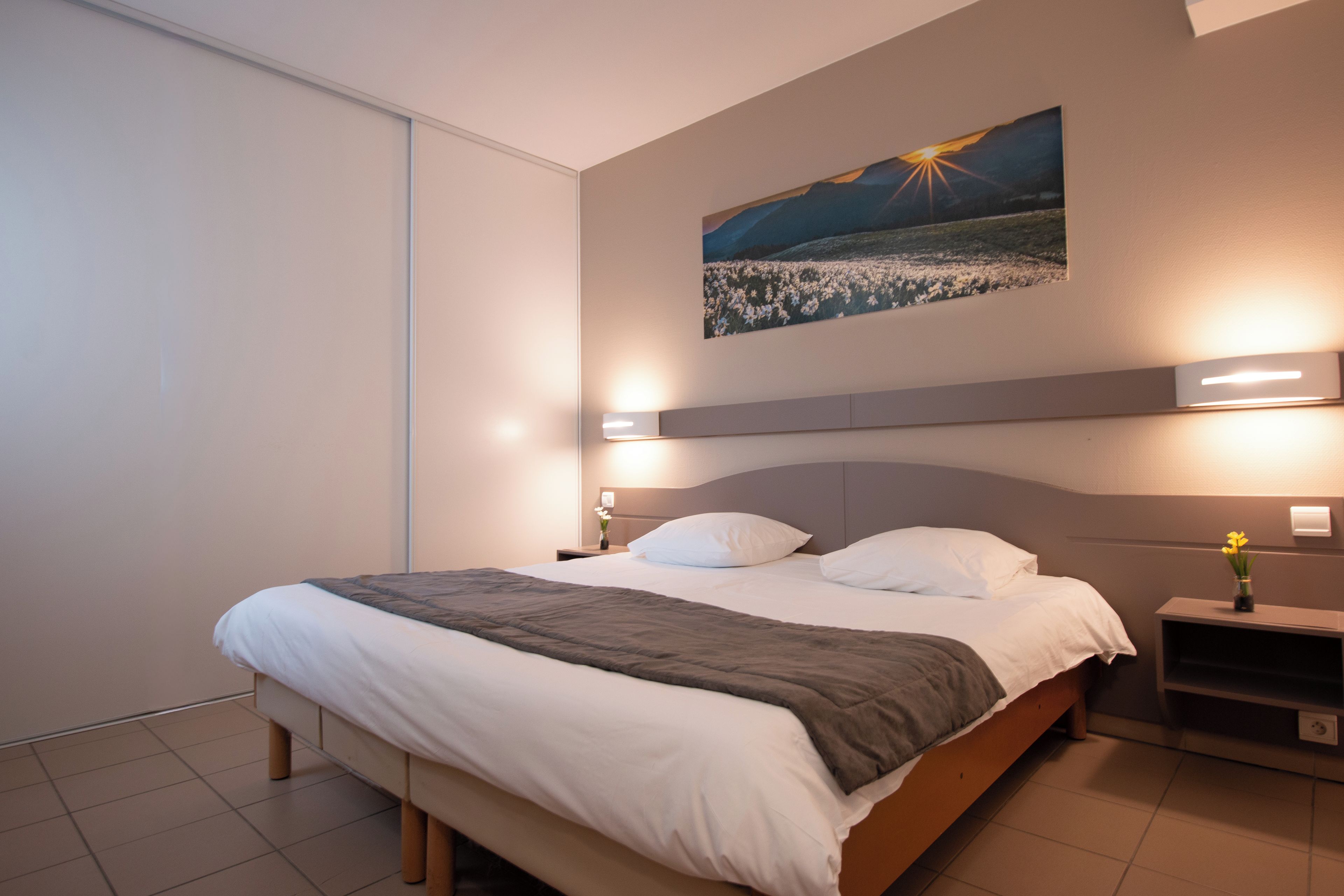 Una habitación de hotel moderna con una cama grande, mesitas de noche y un cuadro colgado en la pared.