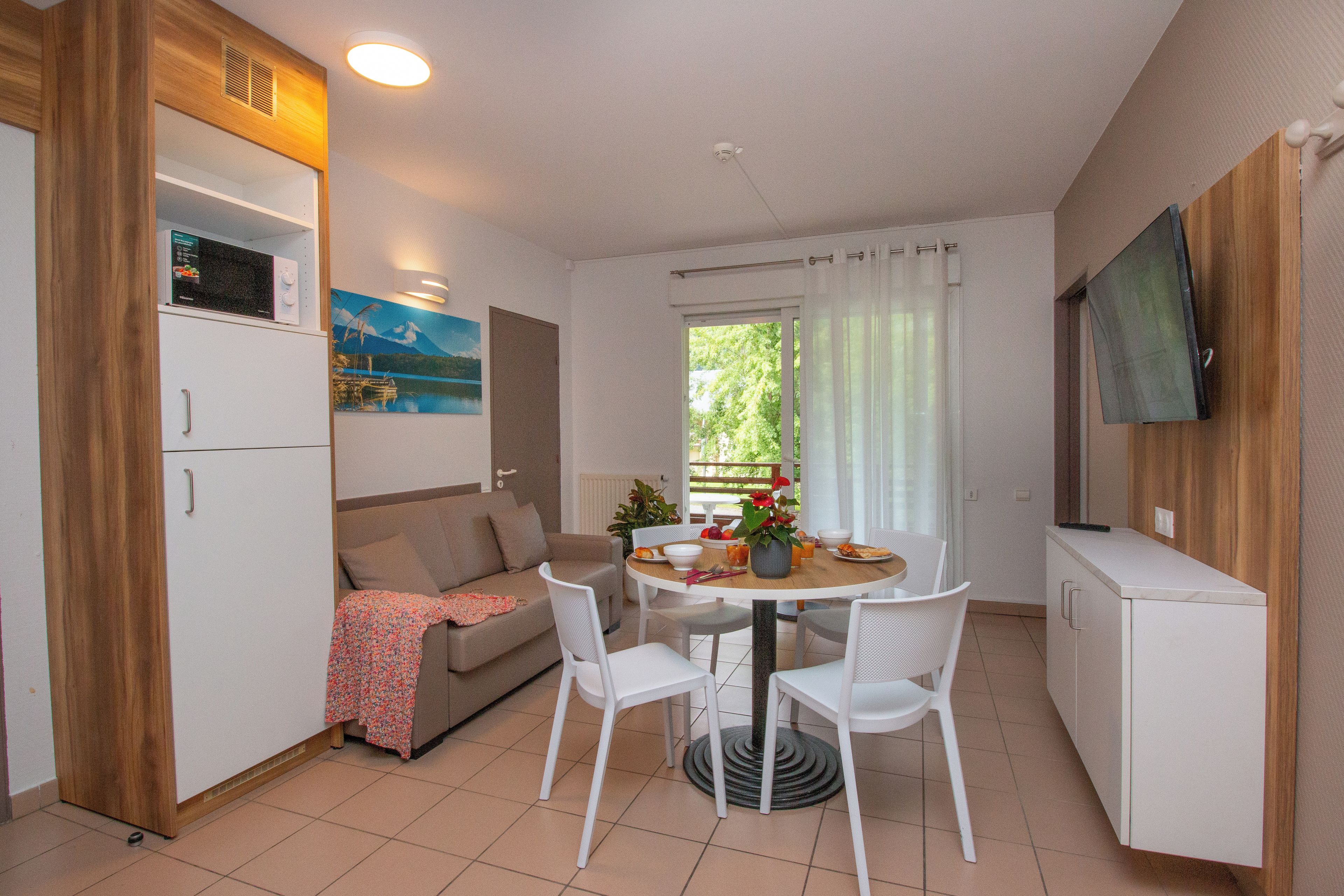 Un espacio habitable compacto con kitchenette, zona de comedor y sofá.