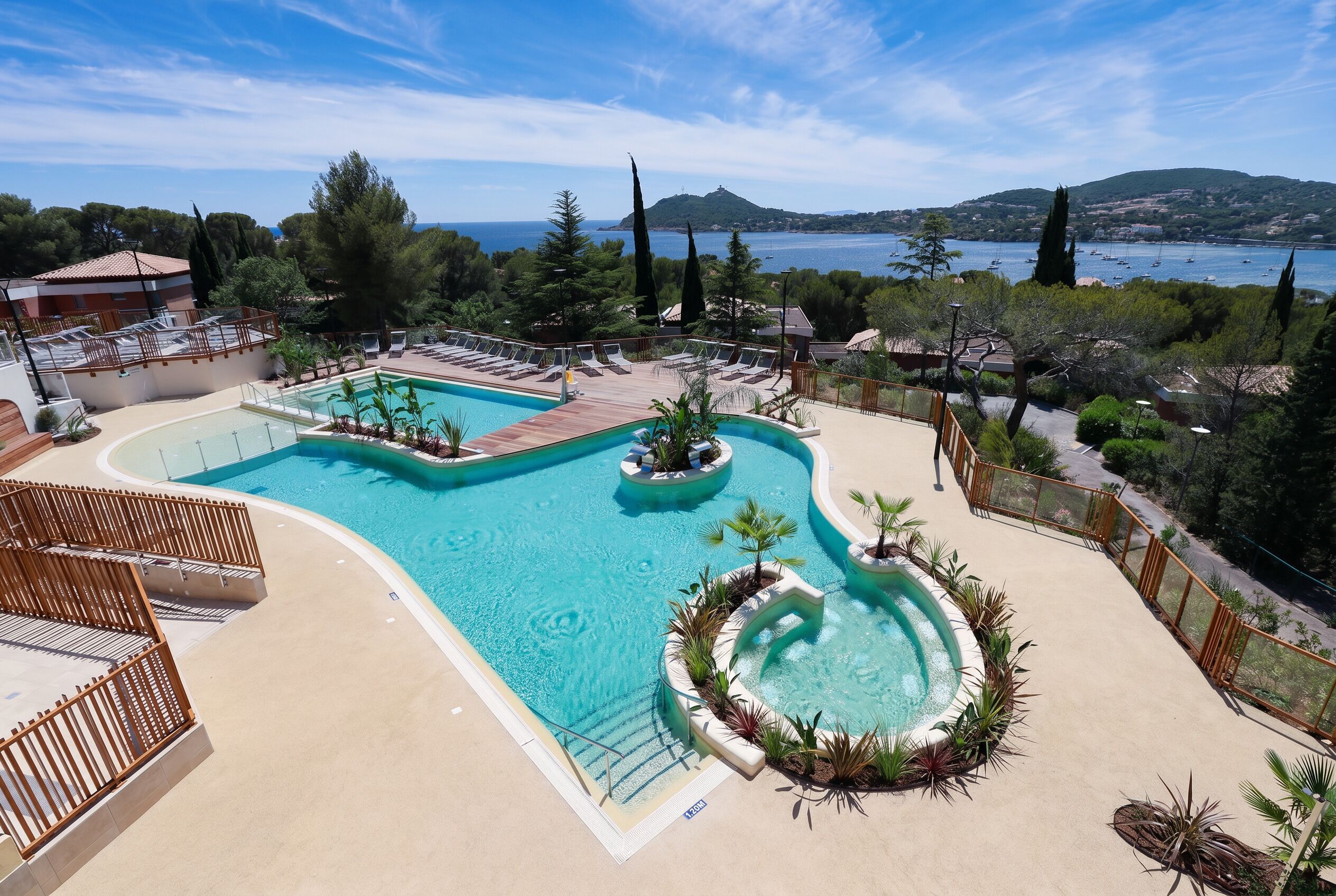 A pool area with lounge chairs and a view of the sea.