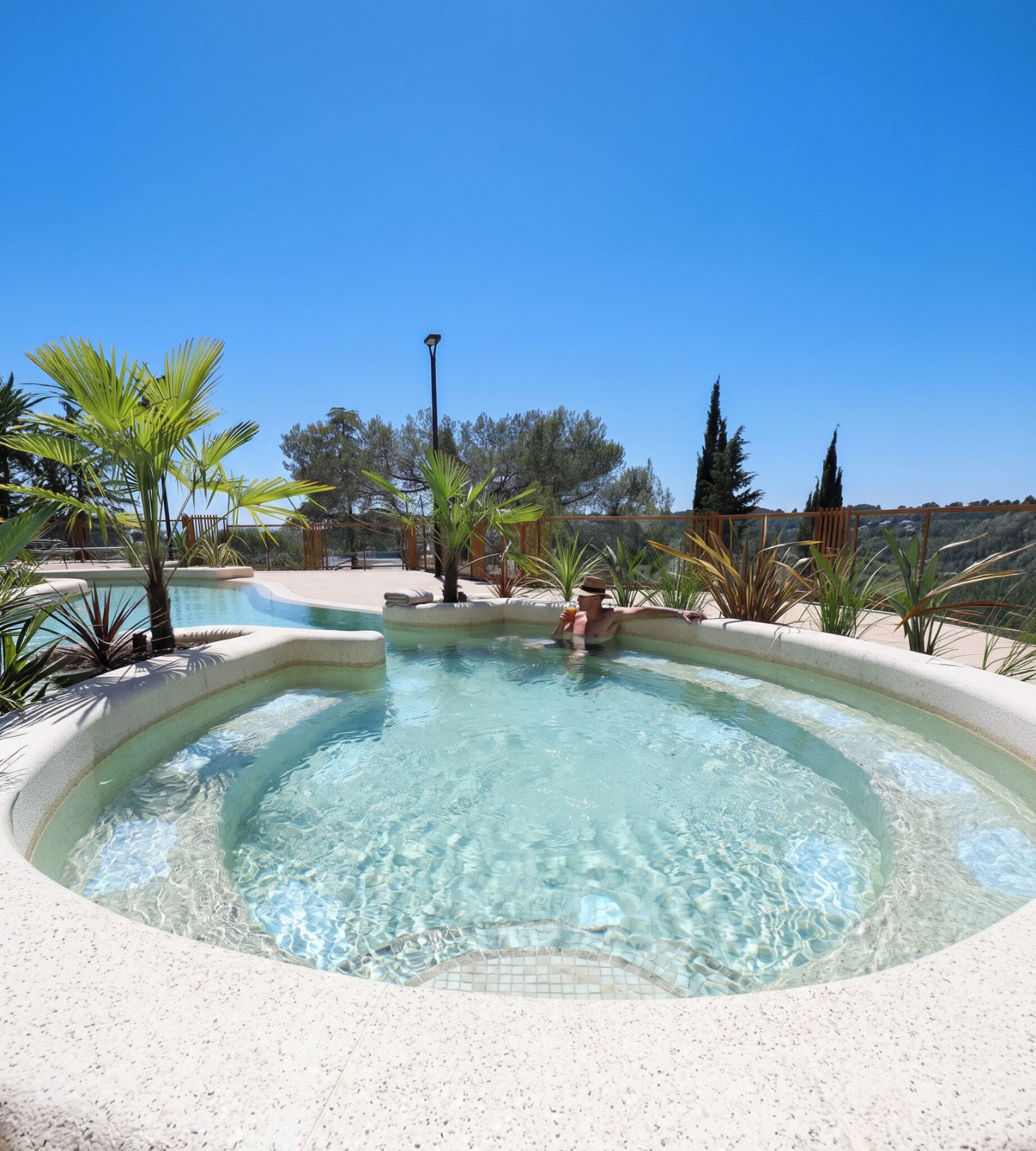 Un jacuzzi rodeado de plantas y un cielo despejado.