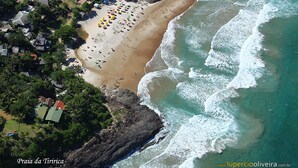 Vue aérienne de la plage de Praia da Tiririca, avec son rivage sablonneux, ses vagues et une forêt verdoyante et dense.