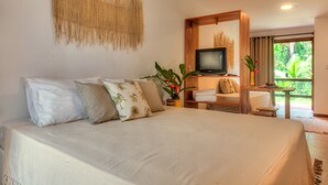 Une chambre avec un grand lit, une télévision et une vue sur la verdure environnante.