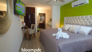 Ein Hotelzimmer mit Bett, Fernseher, Deckenventilator und Klimaanlage.