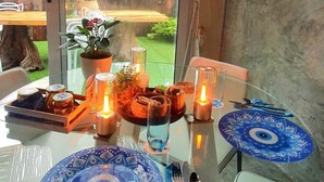 Ein Esstisch mit blauen Tellern, Kerzen und einer Glasvase mit Blumen.