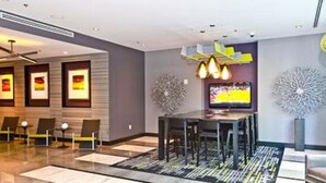 A modern hotel lobby with a glass partition, a dining area with a table and chairs, and decorative wall art. - Heaven on Baltimore Downtown Fully Furnished Apartments (Baltimore)