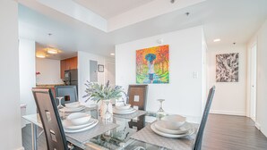 A modern dining area with a glass-top table, white plates, and a vase of flowers. - Heaven on Baltimore Downtown Fully Furnished Apartments (Baltimore)
