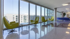 A modern lobby with large windows, yellow chairs, and a blue seating area. - Heaven on Baltimore Downtown Fully Furnished Apartments (Baltimore)