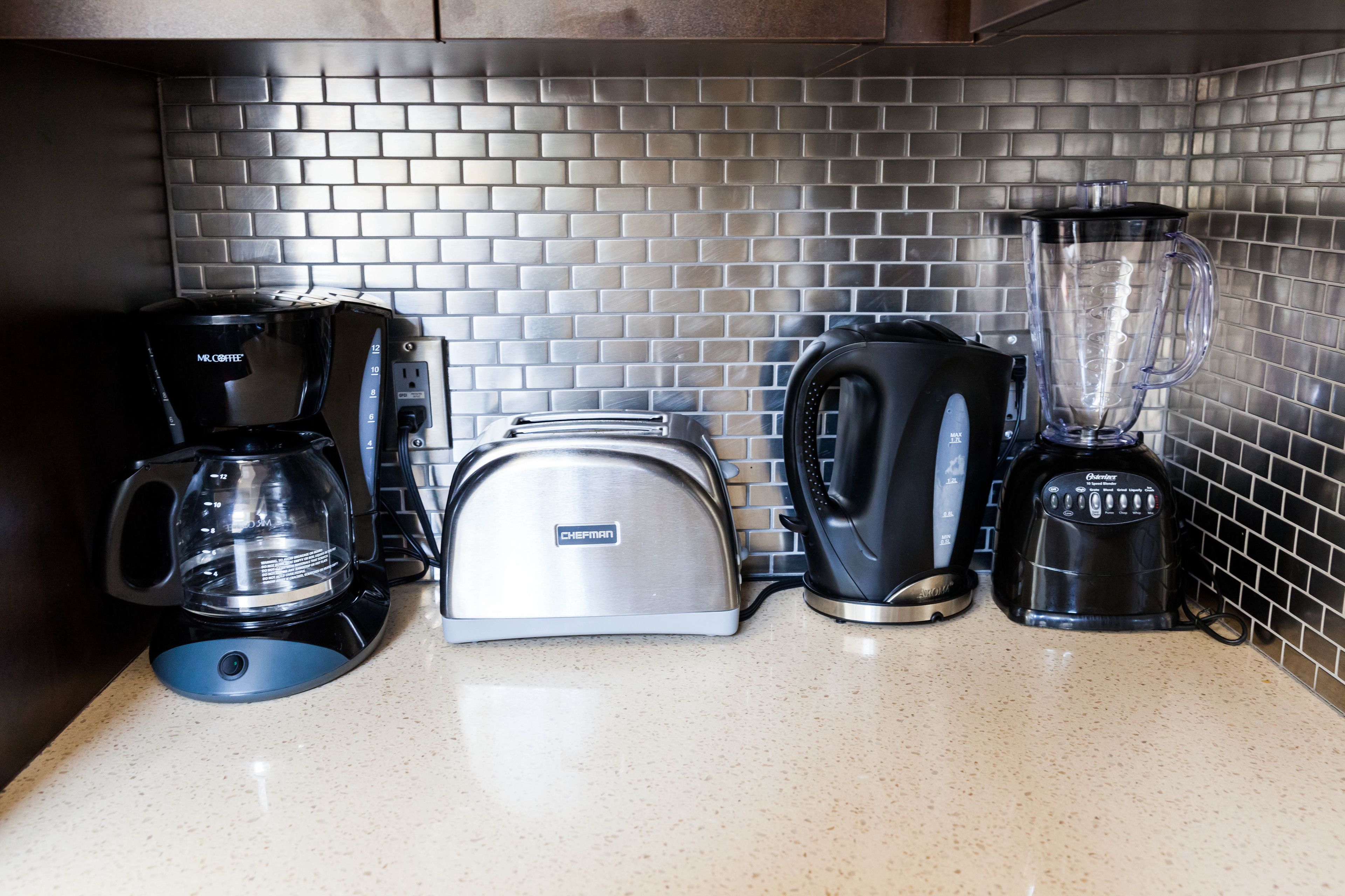 A kitchen counter with a coffee maker, toaster, and blender.