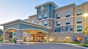A hotel with a stone facade, a covered entrance, and a sign indicating it is a Homewood Suites by Hilton. - Homewood Suites by Hilton New Hartford Utica (New Hartford)