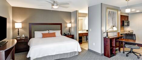 Une chambre d’hôtel équipée d’un lit, d’un bureau, d’une chaise, d’une télévision et d’un ventilateur de plafond.