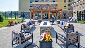 An outdoor patio area with seating, a pergola, and a stone fireplace. - Homewood Suites by Hilton New Hartford Utica (New Hartford)